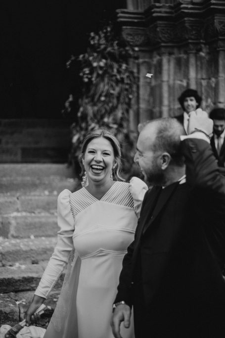 Pareja sonriente en un evento al aire libre, con gente en el fondo.