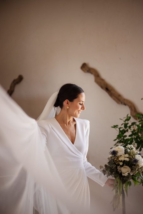 Mujer en vestido de novia sosteniendo un ramo de flores con fondo natural.