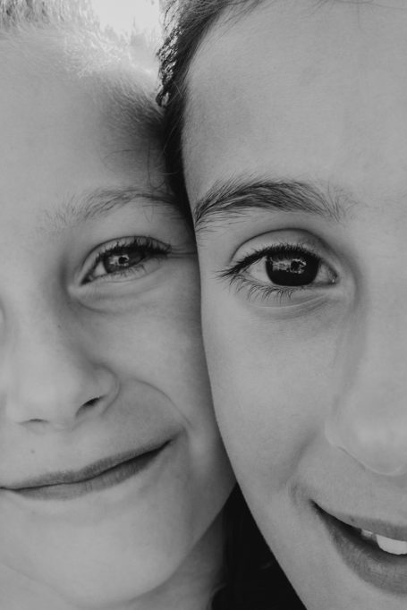 Dos niños sonriendo, uno al lado del otro en blanco y negro.