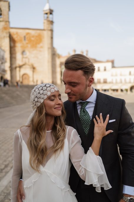 Pareja feliz en un entorno al aire libre, vestidos elegantemente, sonriendo uno al otro.